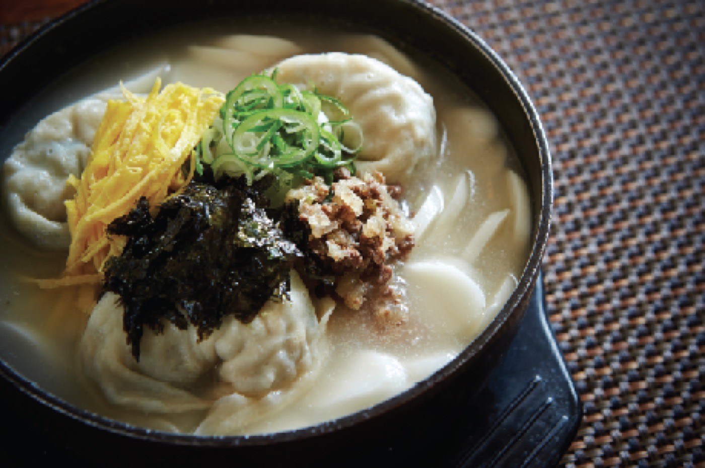 Dumpling and rice cake soup garnished with seaweed and egg