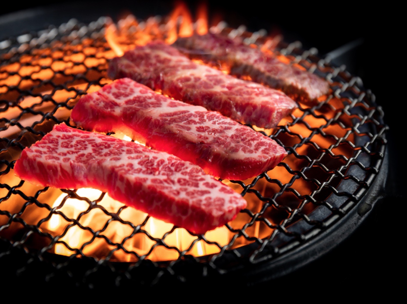 Marbled beef searing over charcoal flames