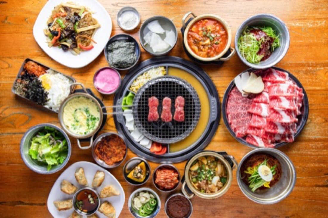 Top-down full Korean BBQ table with stews, rice and side dishes
